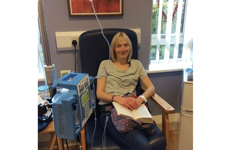 Mulher exausta cuida dos filhos após sessão de quimioterapia