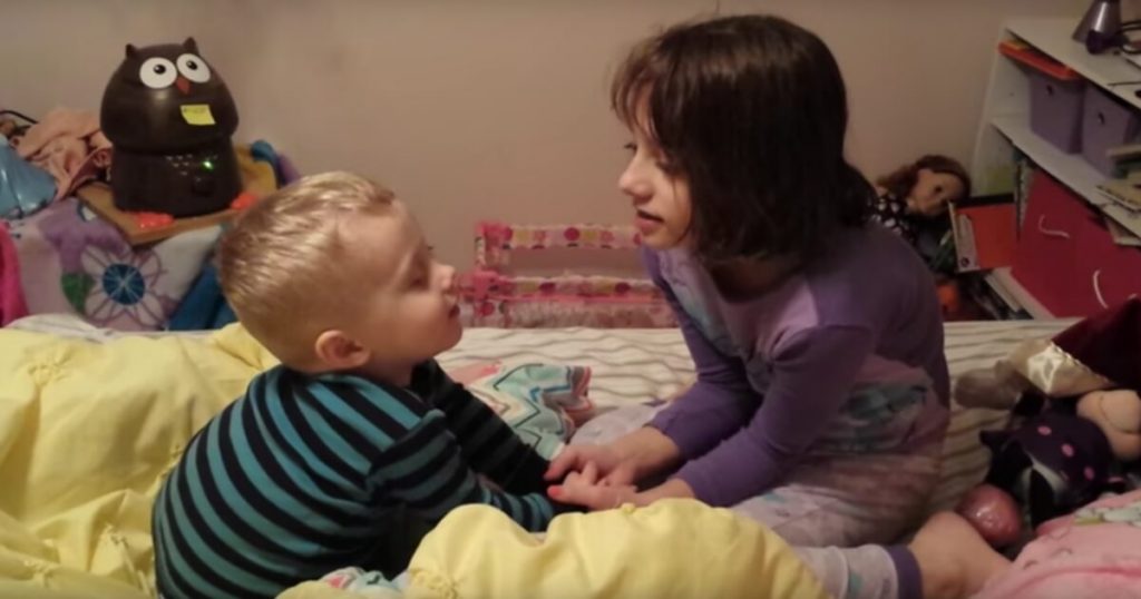 Menina ensina irmão mais no novo a rezar