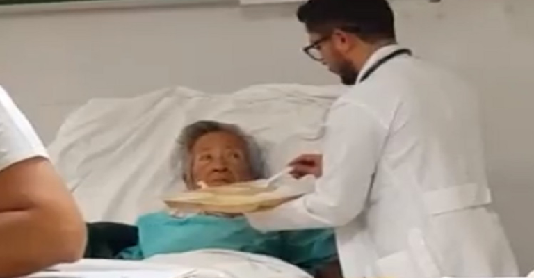 Médico para tudo o que está fazendo e dá comida na boca de paciente idosa em gesto emocionante