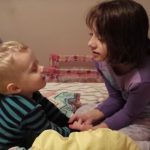 Menina ensina irmão mais no novo a rezar