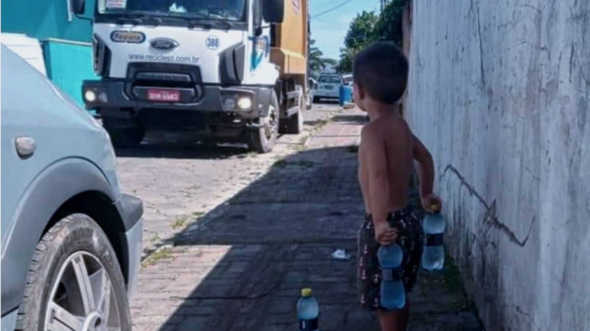 Garoto de dois anos recebe os coletores de lixo com garrafas de água gelada.
